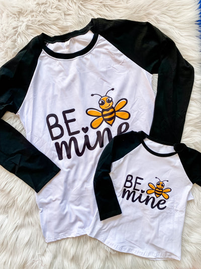 Matching mommy and me raglan shirts with black long sleeves, white background, Be Mine written on the front with a yellow and black smiling bumblebee. 