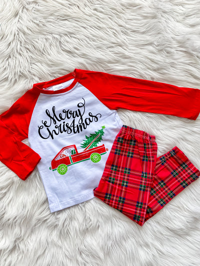 Kids Christmas Pajamas with red plaid bottoms and long sleeve top that says Merry Christmas. Top also has a red truck with a tree in the back. 