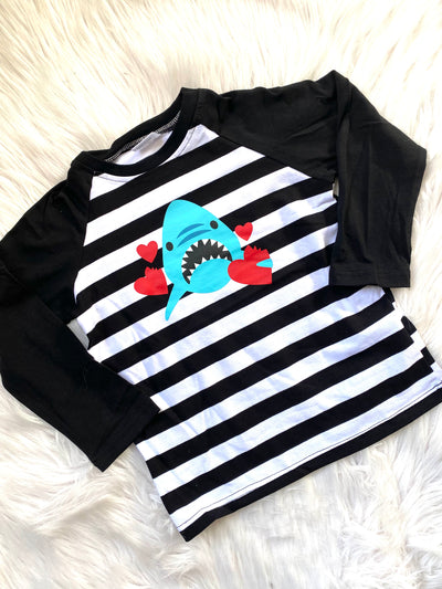 Long black sleeves unisex kid's raglan shirt with black and white stripes and a blue shark holding red hearts. 