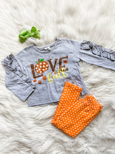 Girls two piece leggings set. Girls long sleeve gray shirt with ruffle details on the sleeve and glitter graphic Love Fall on the front. Matching orange leggings with white polka dots. Tulips and Twirls Children's Boutique in Orlando, Florida.