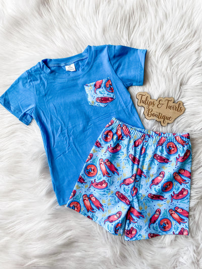 Boys summer outfit with blue short sleeve shirt and matching otter print shorts with elastic waist band. Orlando children's boutique clothing.