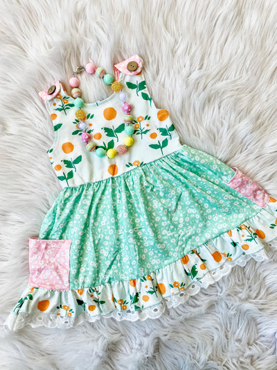 Girls spring dress with flower patterns, pockets, and button straps with eyelet ruffles at the bottom. Girls Boutique Dresses from Tulips & Twirls Orlando Girls Boutique.