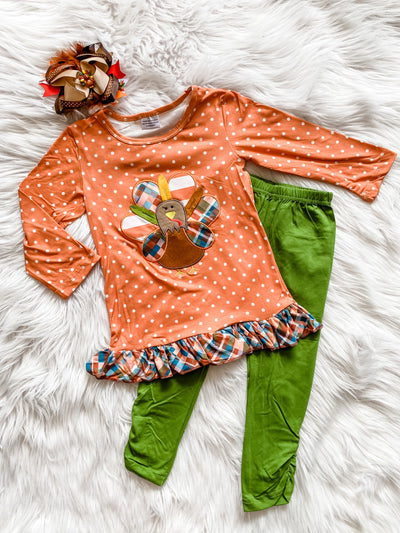 Girls two piece Thanksgiving set with long sleeve orange and white polka dots, embroidered turkey and plaid ruffle hem, and green leggings.