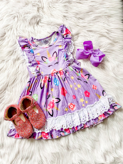 Girls purple dress with white lace trim, flutter sleeves and a unicorn print. 