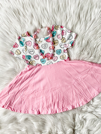 Girls twirl dress with full pink skirt and white top with conversation heart prints on top. Pink and white bubblegum necklace. 