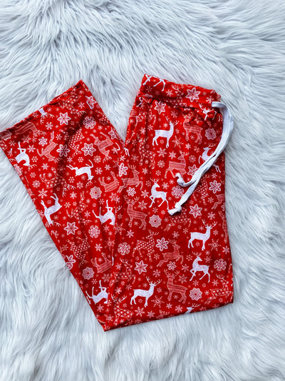 Men's lounge pants with red background and white reindeer and snowflakes and a drawstring at the waist. 